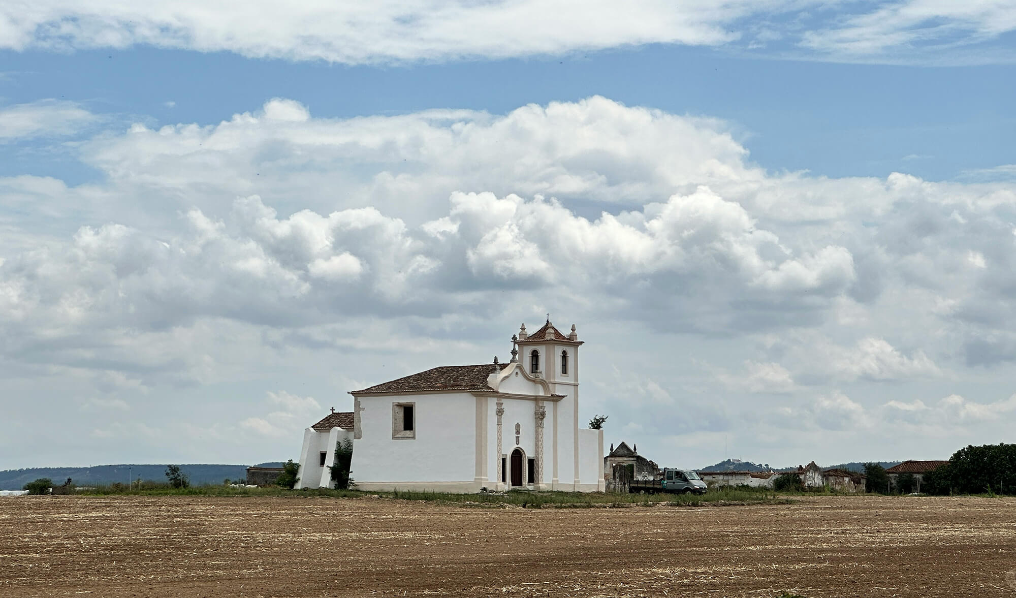Follow the energy through a peaceful white countryside church beneath dramatic clouds in a quiet rural landscape.